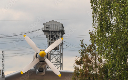 Wing of an airplane with a propeller on a background of a gray tower photo