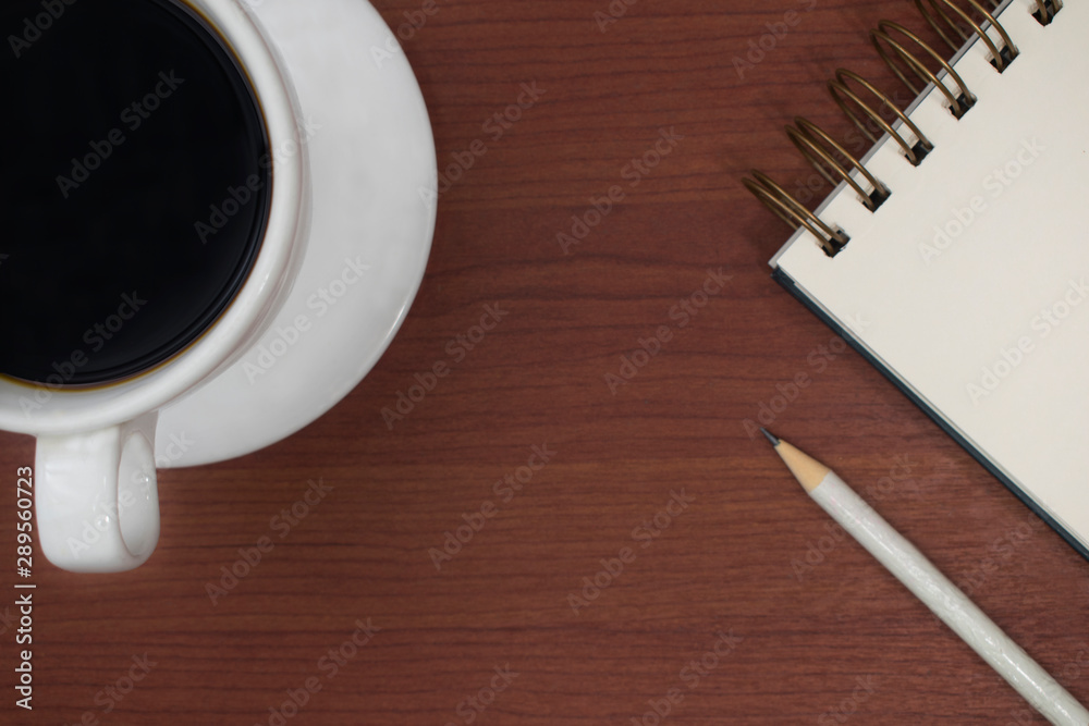 coffee cup and notebook on the wooden table seen from above
