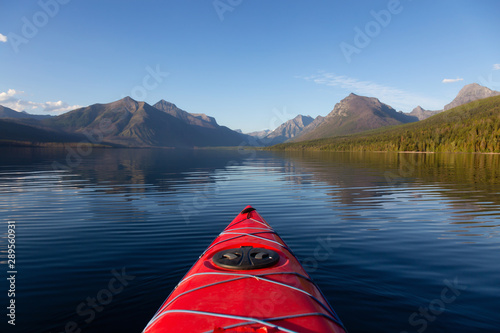 Kayaking in Lake McDonald during a sunny summer evening with American Rocky Mountains in the background. Taken in Glacier National Park, Montana, USA.