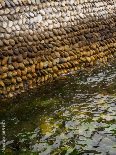 Closeup of a stone wall on the edge of an industrial pier, wet with water and algae. Miyajima Island, Hiroshima, Japan. Vertical orientation. Travel and nature. photo