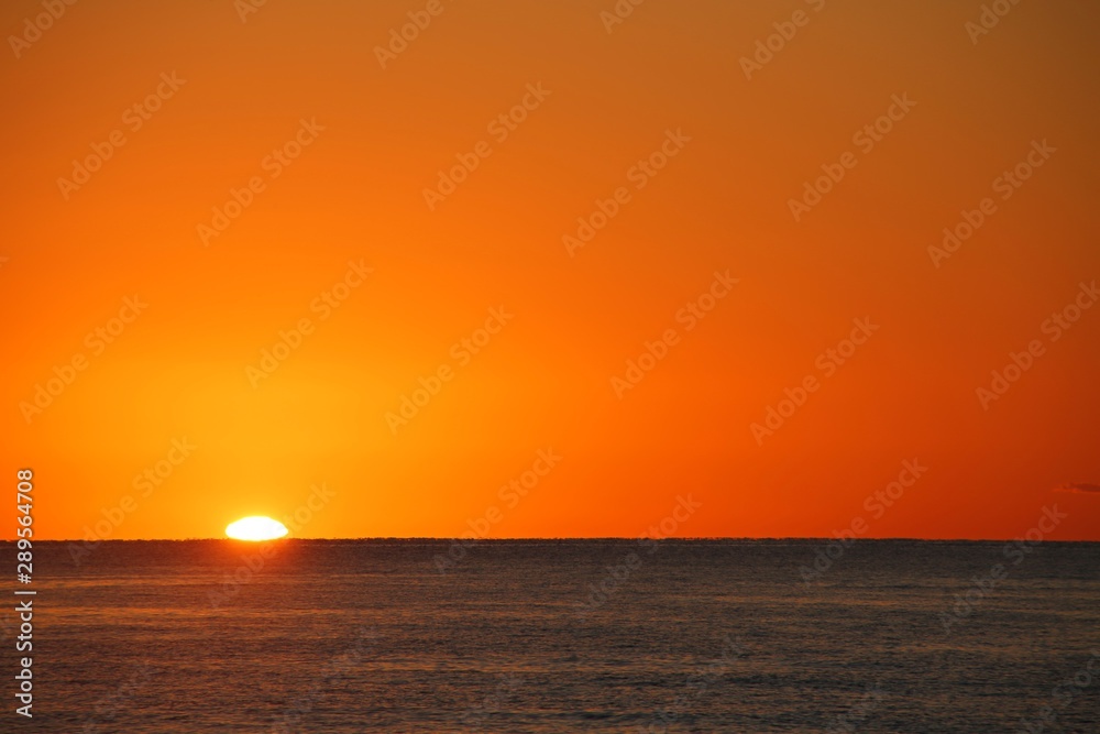 Beautiful Orange Sunrise over the Atlantic Ocean Creating Glowing Ripples on the Blue Water in Florida in a Clear Dry Morning in April