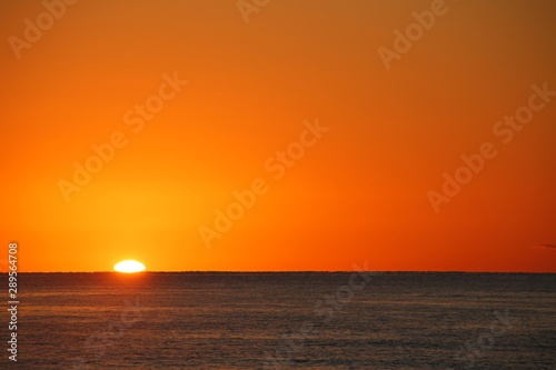 Beautiful Orange Sunrise over the Atlantic Ocean Creating Glowing Ripples on the Blue Water in Florida in a Clear Dry Morning in April