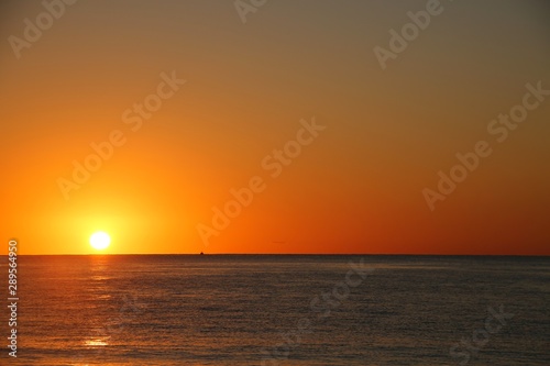 Beautiful Orange Sunrise over the Atlantic Ocean Creating Glowing Ripples on the Blue Water in Florida in a Clear Dry Morning in April © kthx1138