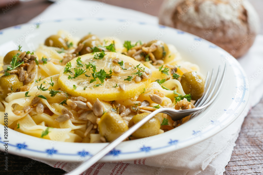 Sicilian tagliatelle pasta with lemon, garlic and olives, garnished with sunflower seeds.