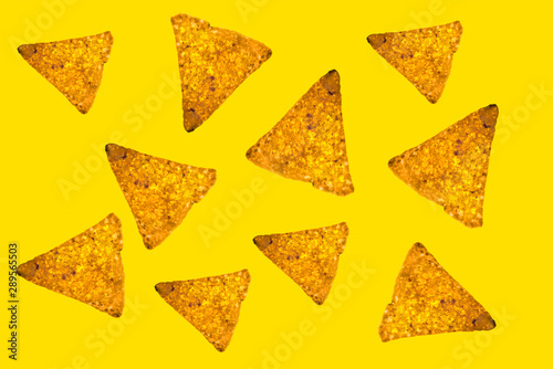 Abstract bright background of whole randomly located triangular nachos slices on yellow color