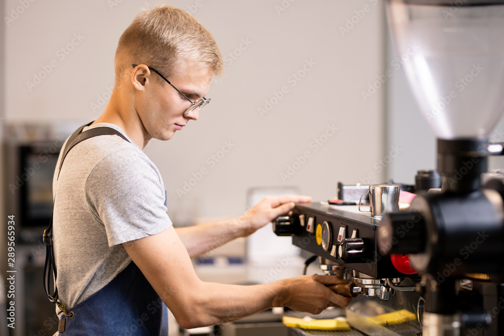 Young owner of small cozy cafe going to prepare coffee for his clients Young owner of small cozy cafe going to prepare coffee for his clients
