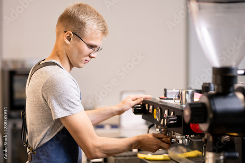 Young owner of small cozy cafe going to prepare coffee for his clients