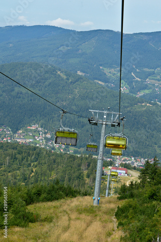 Chairlift in the Silesian Beskids mountains with Szczyrk town in the distance and forest in the background