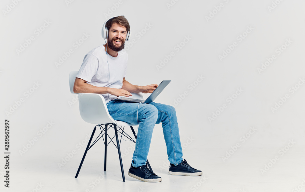 young man sitting on a chair and working on his laptop young man sitting on a chair and working on his laptop