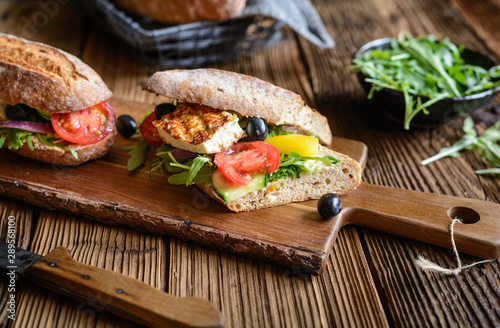 Wholemeal vegetarian baguette stuffed with grilled white cheese, arugula, tomatoes, black olives, bell pepper and red onion