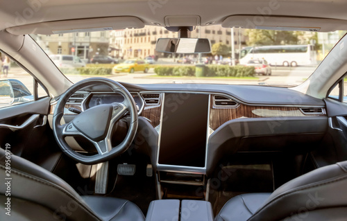 Interior of a modern electric car on a sunny day. the city is blurred in the background © Artemiy