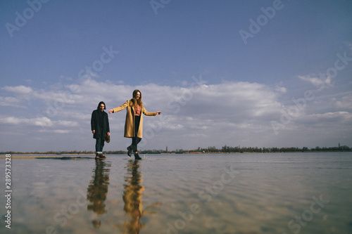 Young couple in warm coats having fun on the river bank. Walking on the river