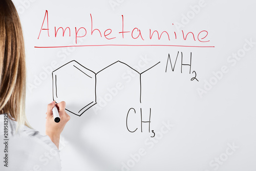 cropped view of woman writing chemical formula on white board