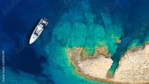 Aerial top view luxury inflatable rib speed boat docked in mediterranean emerald rocky bay with crystal clear sea