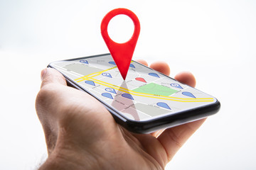 Human Hand Holding Cellphone With Navigation Sign