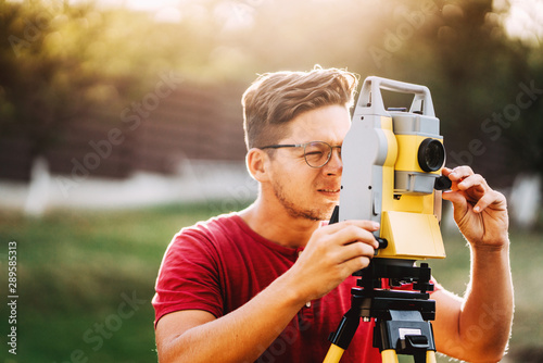 Surveyor engineer working with total station on garden elevation