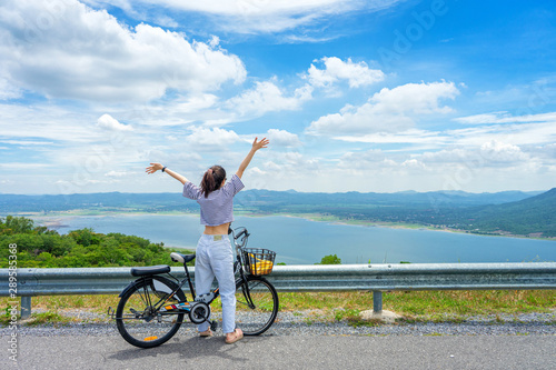 Young woman standing near bicycle and happy in vacation time at the park.
