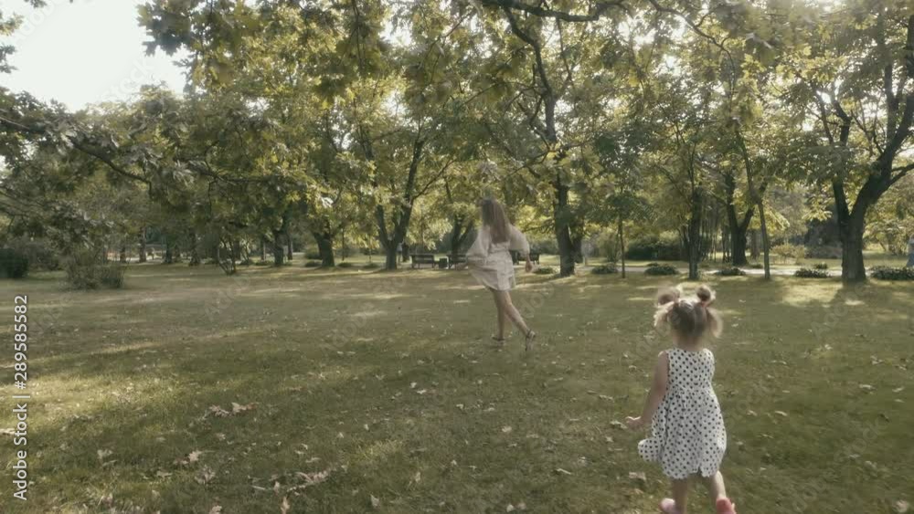 Baby girl with mother running through the grass in the summer sunlight in park. Baby have fun. Happy family concept. Child with mother running. Baby girl with mother running through the grass in the summer sunlight in park. Baby have fun. Happy family concept. Child with mother running.