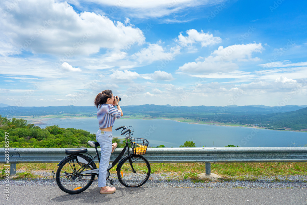 Young woman standing near bicycle and happy in vacation time at the park. Young woman standing near bicycle and happy in vacation time at the park.