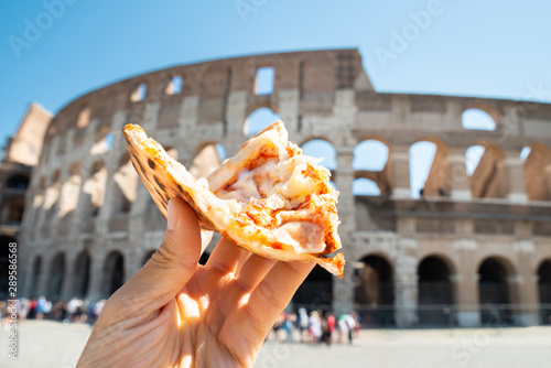 Fototapeta Naklejka Na Ścianę i Meble -  Hand Holding Italian Pizza Near Colosseum