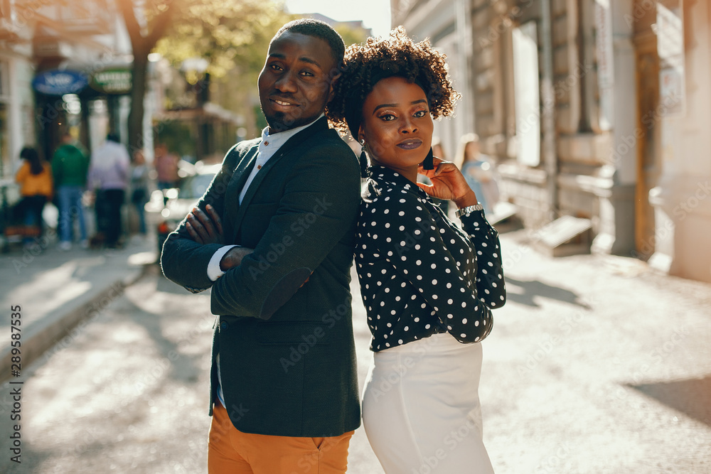 A young and stylish dark-skinned couple standing in a sunny city