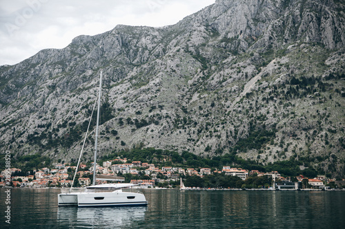 Beautiful view of the mountains, coastal city, sea and a sailboat or boat in the foreground. Natural landscape in Montenegro.
