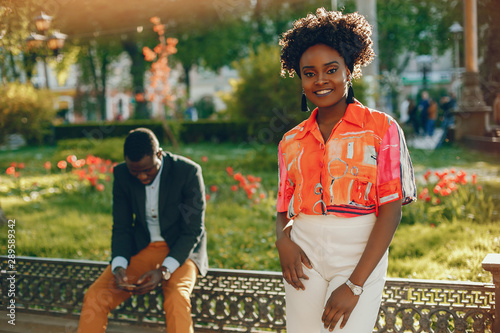 A young and stylish dark-skinned couple sitting in a sunny city