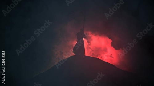 Christian Monk in a Tunic Leans on a Cross Under a Storm photo