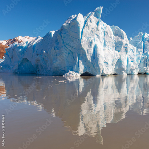 Ice peak of the Grey Glacier with a reflection in the Grey lake and the Andes mountain range in the background  Torres del Paine national park  Patagonia  Chile.