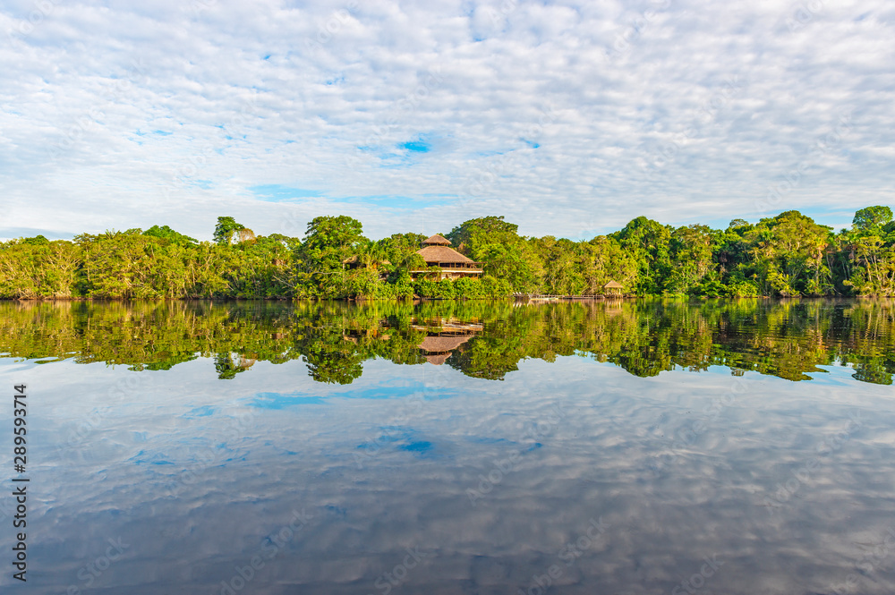 Jungle lodge located in the Amazon Rainforest by a lagoon. The tributaries  of the Amazon river traverse the countries of Guyana, Ecuador, Peru,  Brazil, Colombia, Venezuela, Suriname and Bolivia. Stock-Foto | Adobe