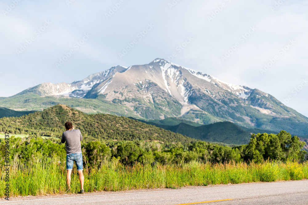 Man photographing mount Sopris mountain in Carbondale, Colorado town view with snow mountain peak and sky in summer during sunset