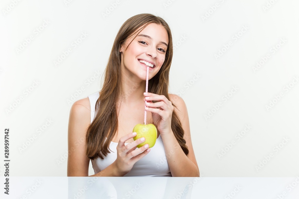 Young caucasian woman drinking an apple with a straw. Healthy life concept. Young caucasian woman drinking an apple with a straw. Healthy life concept.
