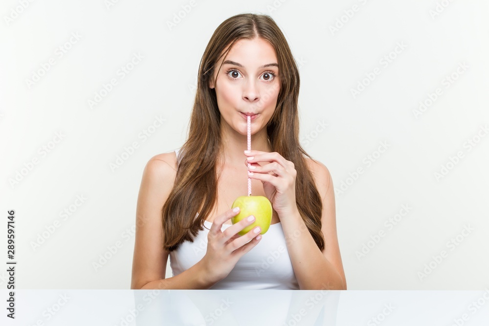 Young caucasian woman drinking an apple with a straw. Healthy life concept. Young caucasian woman drinking an apple with a straw. Healthy life concept.