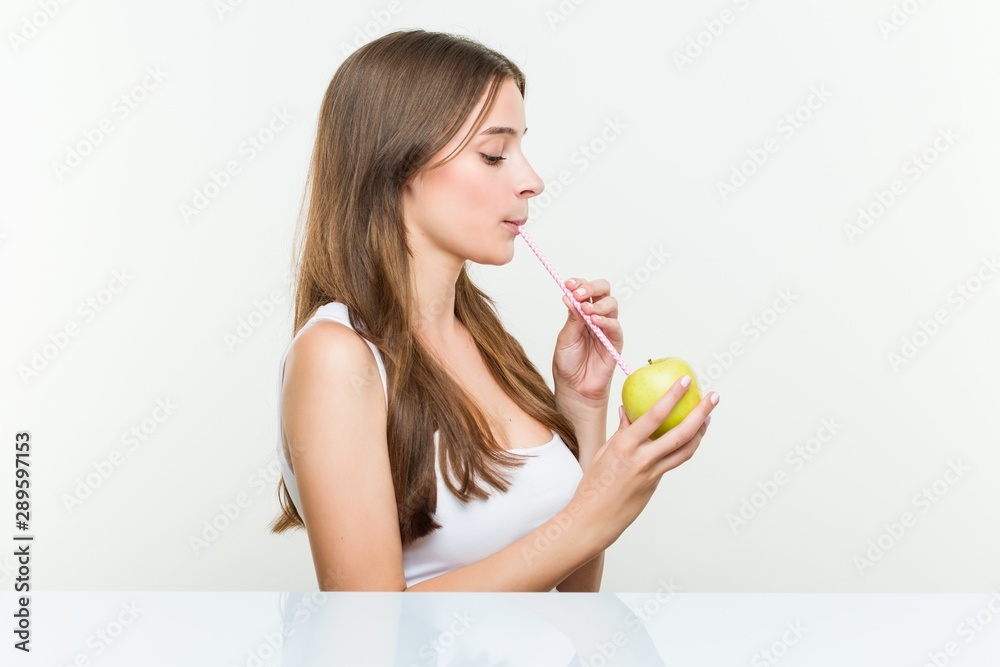 Young caucasian woman drinking an apple with a straw. Healthy life concept. Young caucasian woman drinking an apple with a straw. Healthy life concept.