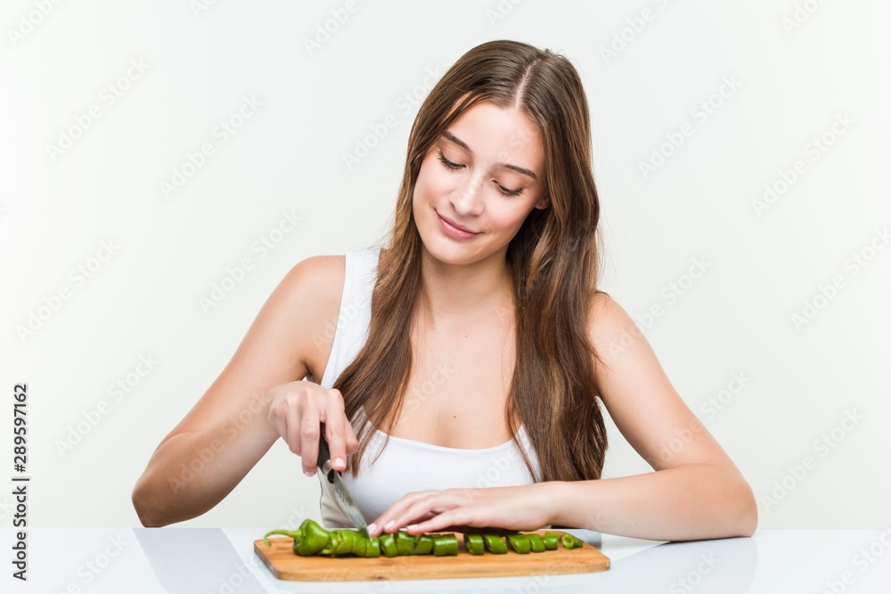 young caucasian woman cutting vegetables young caucasian woman cutting vegetables