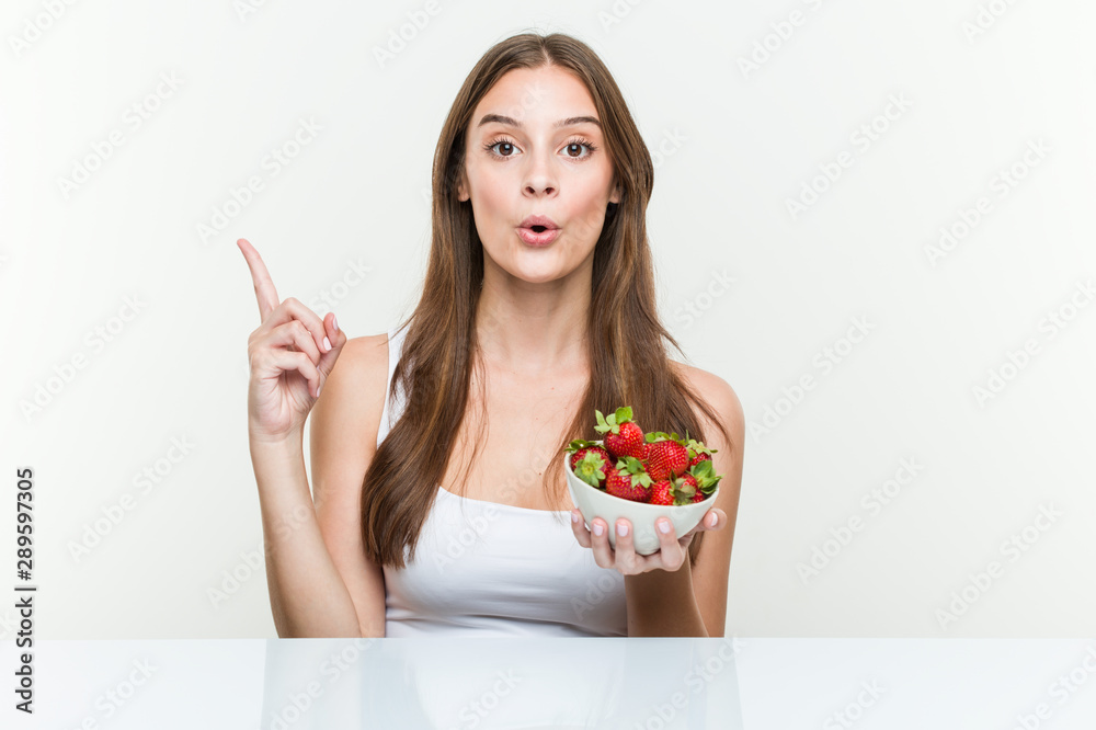 Young caucasian woman holding a strawberries bowl having some great idea, concept of creativity. Young caucasian woman holding a strawberries bowl having some great idea, concept of creativity.