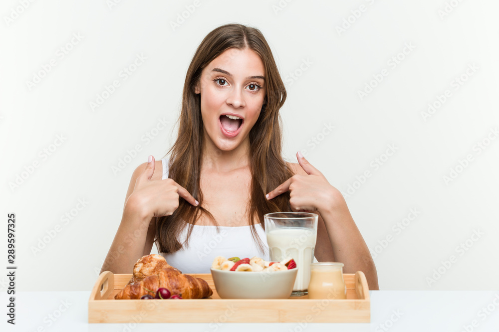 Young caucasian woman having breakfast surprised pointing at himself, smiling broadly. Young caucasian woman having breakfast surprised pointing at himself, smiling broadly.