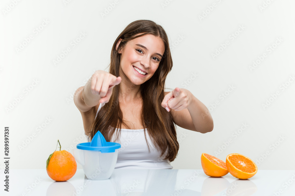 Young caucasian woman with an orange juicer cheerful smiles pointing to front. Young caucasian woman with an orange juicer cheerful smiles pointing to front.