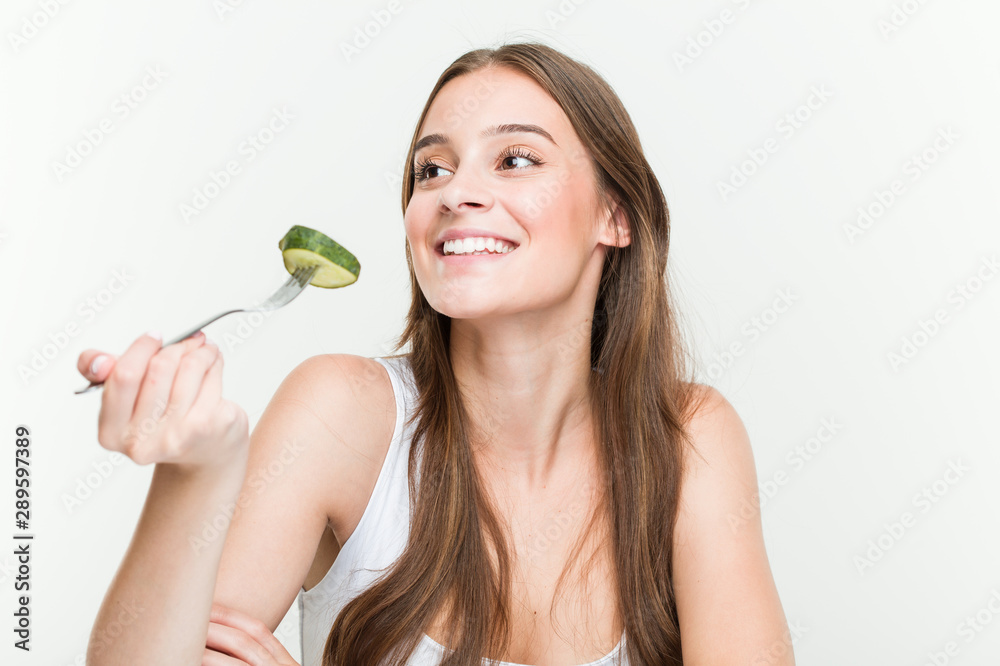Young caucasian woman eating cucumber smiling confident with crossed arms. Young caucasian woman eating cucumber smiling confident with crossed arms.