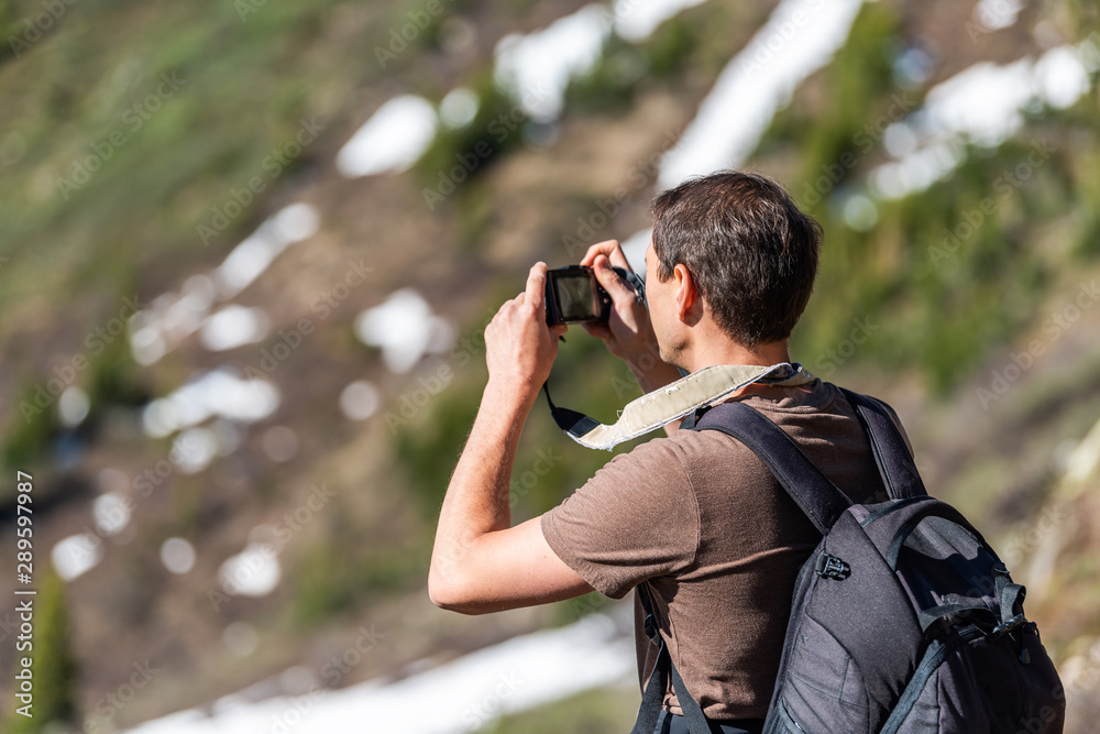 Man taking pictures of view on Linkins Lake trail on Independence Pass in rocky mountains near Aspen, Colorado in early summer of 2019 with snow background