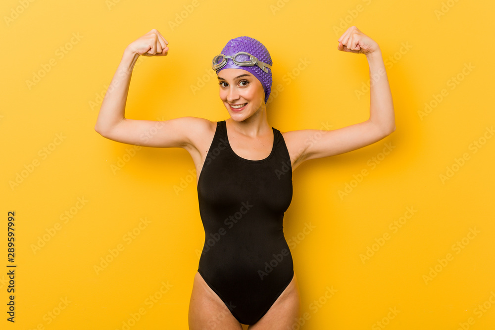 Young swimmer caucasian woman showing strength gesture with arms, symbol of feminine power Young swimmer caucasian woman showing strength gesture with arms, symbol of feminine power