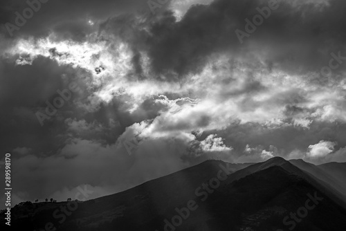 Black and white photograph of the Pichincha volcano seen from Quito city at sunset with a wonderful sunbeam, Andes mountain range, Ecuador.