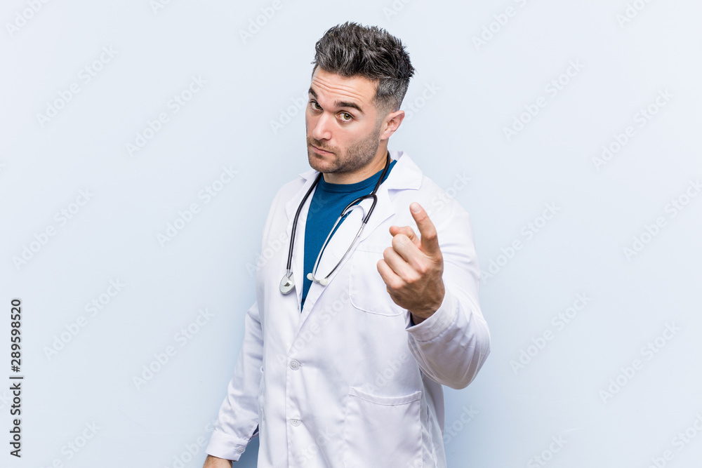Young handsome doctor man pointing with finger at you as if inviting come closer. Young handsome doctor man pointing with finger at you as if inviting come closer.