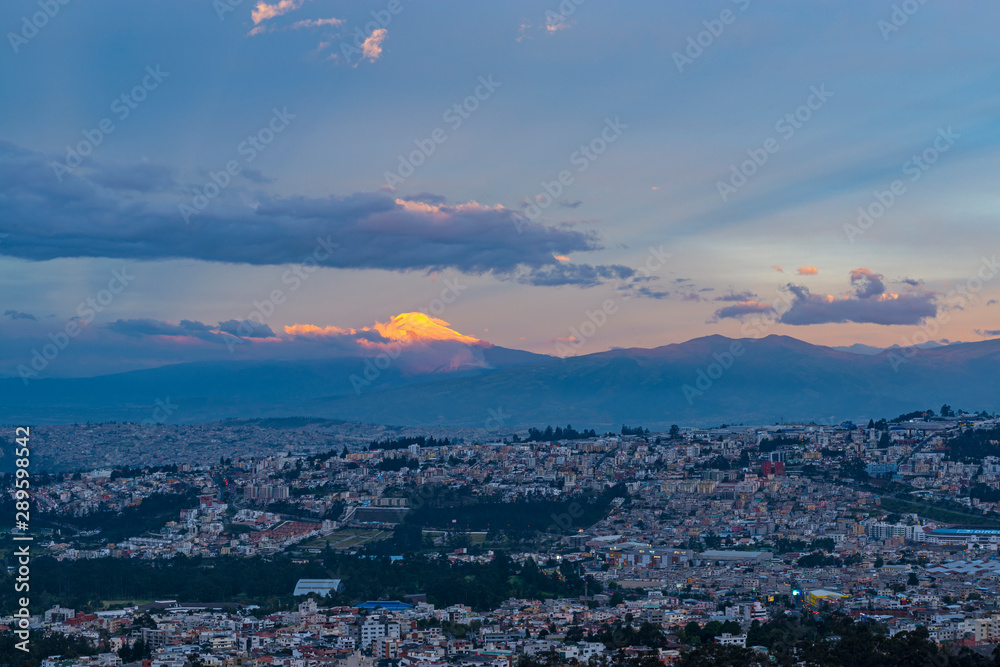 The majestic Cayambe volcano illuminated by the last sun rays at sunset in the city of Quito, Ecuador.