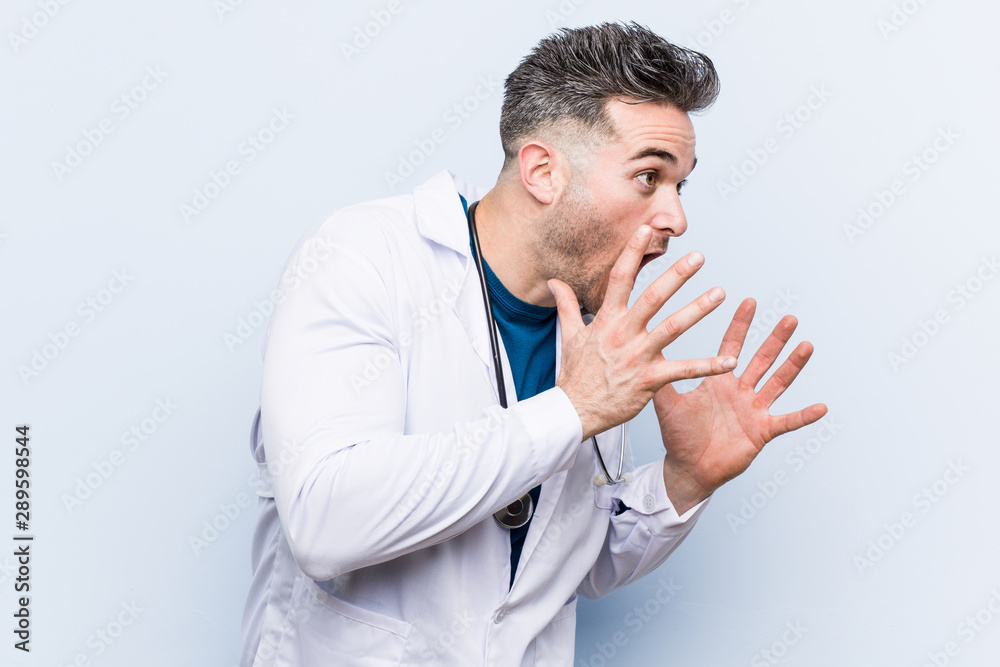 Young handsome doctor man shouts loud, keeps eyes opened and hands tense. Young handsome doctor man shouts loud, keeps eyes opened and hands tense.