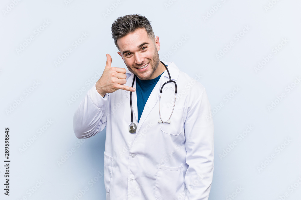 Young handsome doctor man showing a mobile phone call gesture with fingers. Young handsome doctor man showing a mobile phone call gesture with fingers.