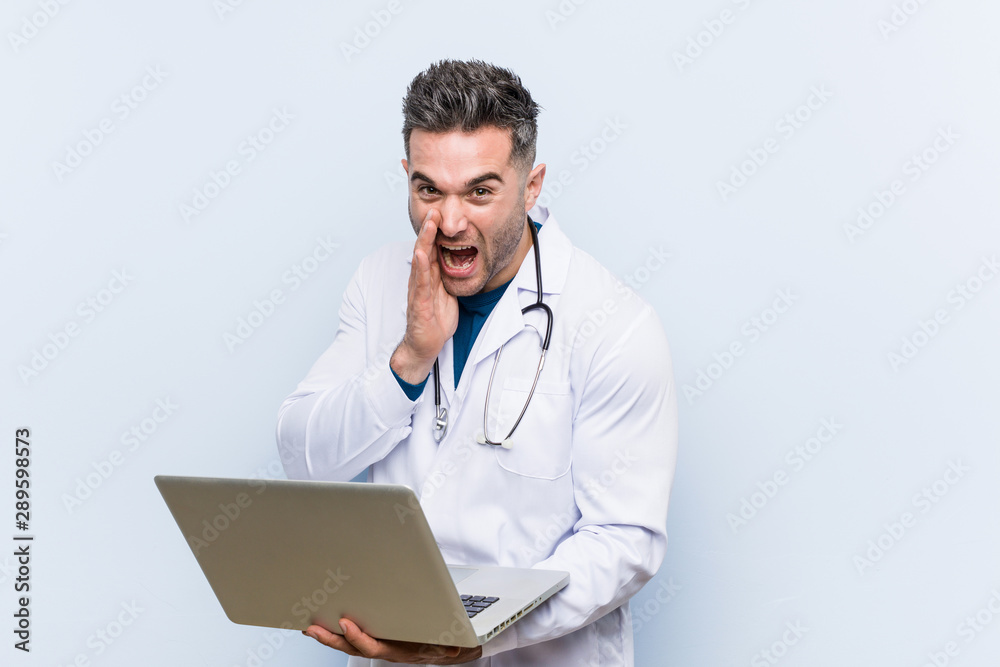 Caucasian doctor man holding a laptop shouting excited to front. Caucasian doctor man holding a laptop shouting excited to front.