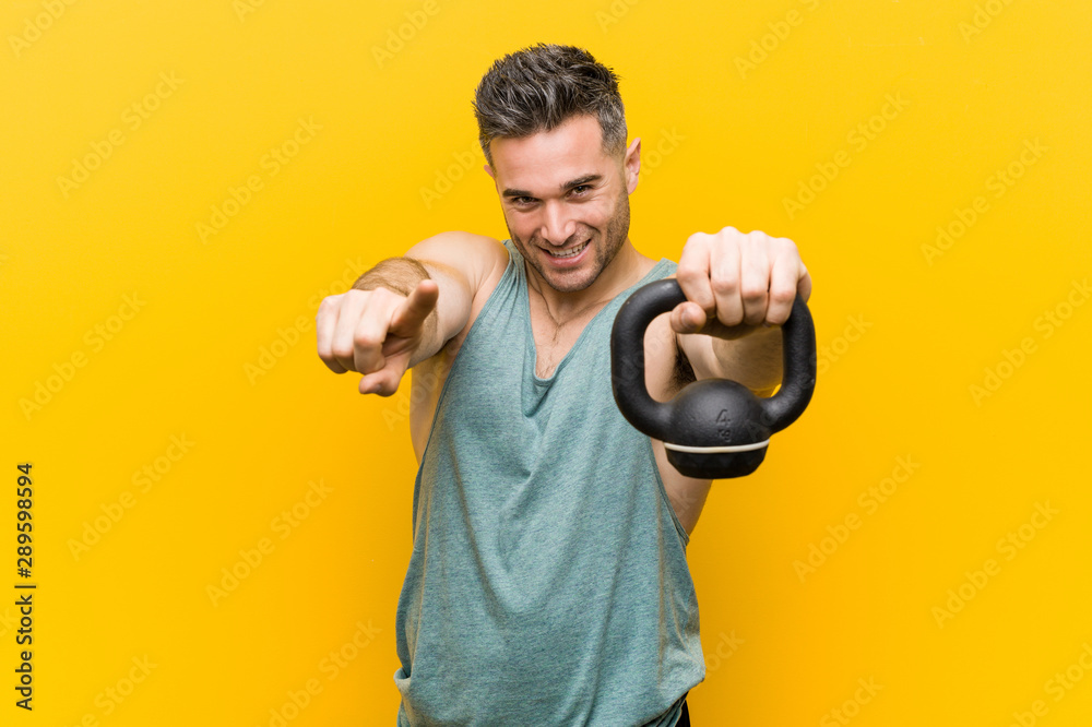 Caucasian man holding a bumbbell cheerful smiles pointing to front. Caucasian man holding a bumbbell cheerful smiles pointing to front.