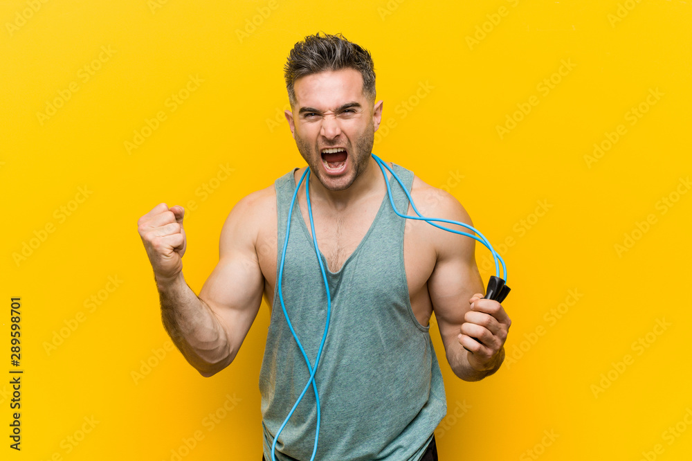 Caucasian man holding a jump rope cheering carefree and excited. Victory concept.