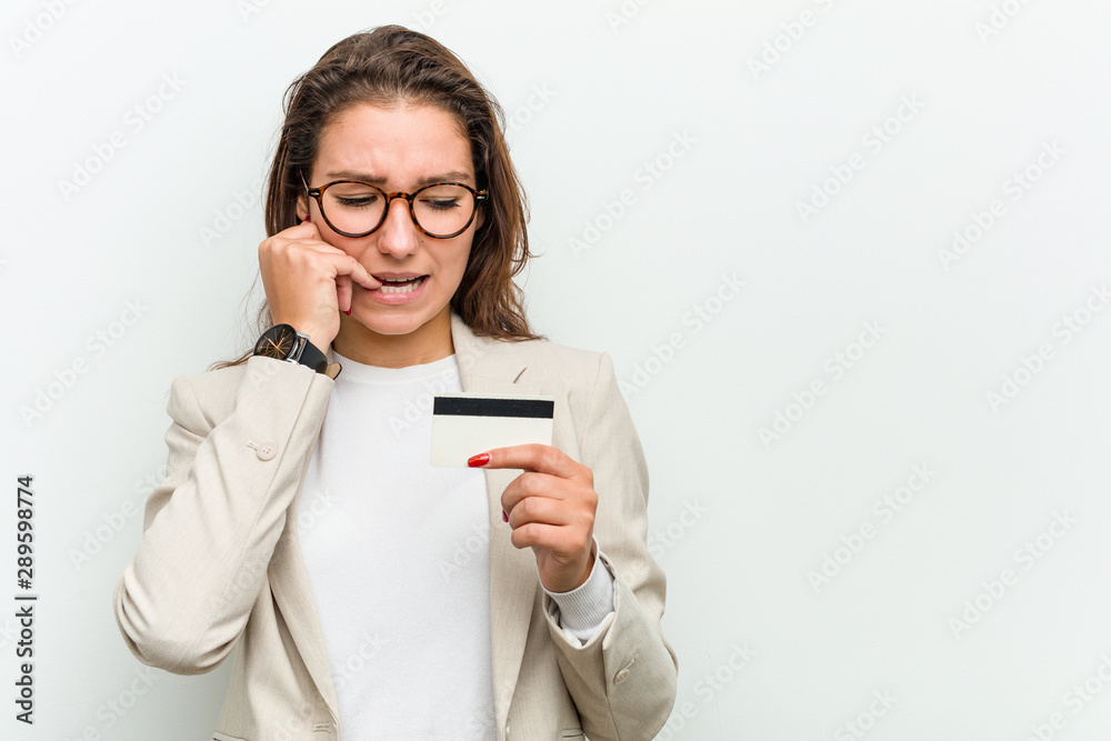 Young european business woman holding a credit card biting fingernails, nervous and very anxious. Young european business woman holding a credit card biting fingernails, nervous and very anxious.